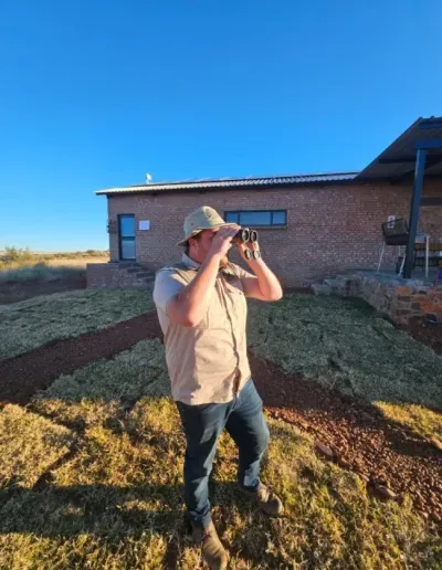 Photo of a man standing outside with binoculars