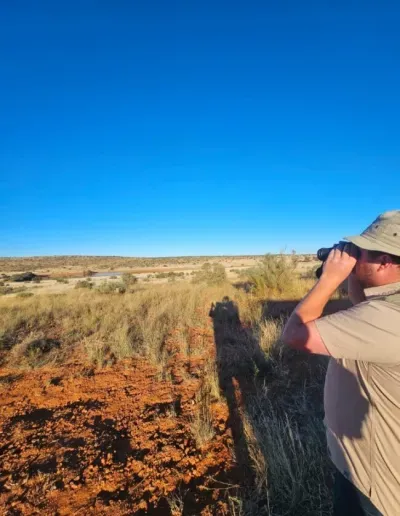 Photo of a man standing outside with binoculars
